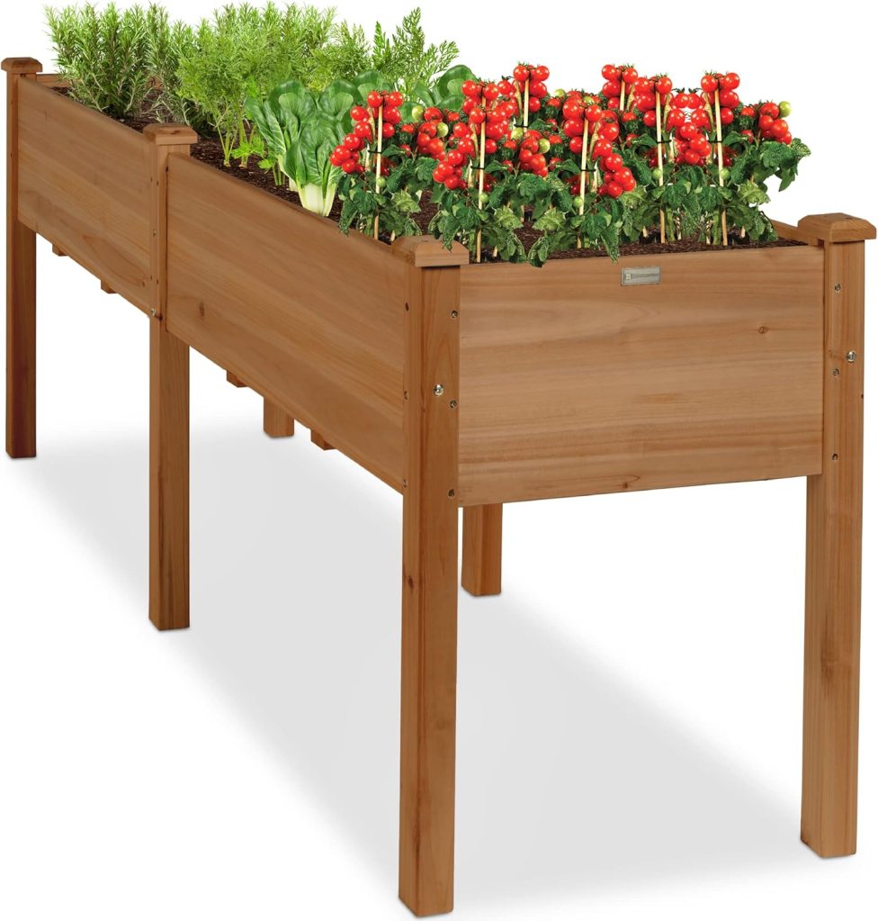 A raised garden bed made of wood featuring various plants including red tomatoes, leafy greens, and herbs, designed for backyard or patio use.