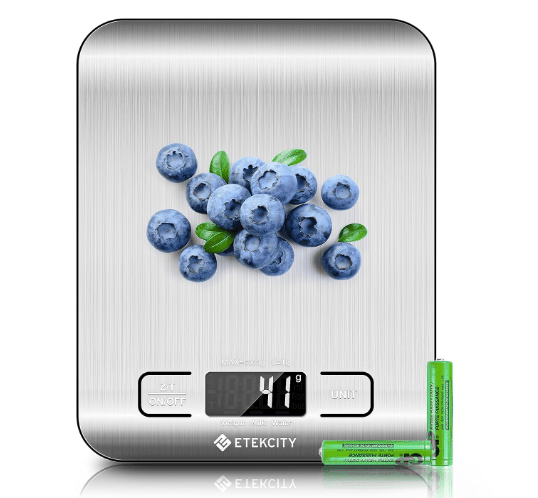 Digital kitchen scale by Etekcity displaying a bunch of blueberries on a stainless steel surface with a digital readout and batteries beside it.