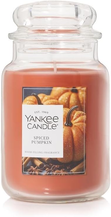 A Yankee Candle Spiced Pumpkin scented candle in a large glass jar, featuring a label with the name and image of pumpkins.