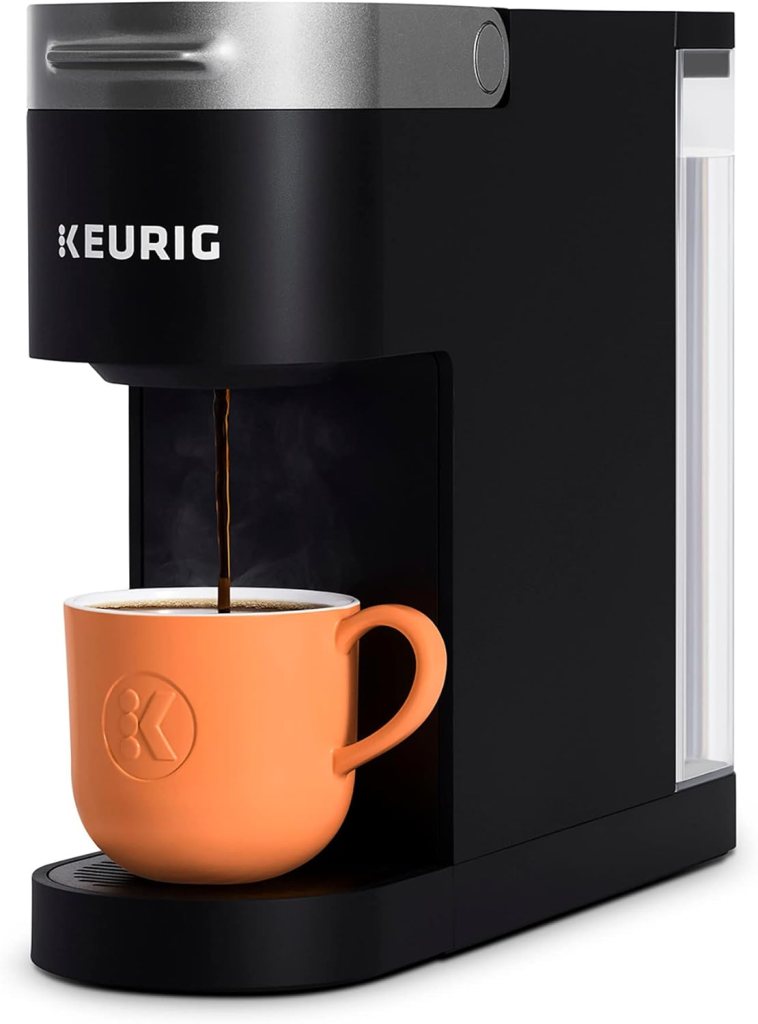 A Keurig K-Slim Single Serve Coffee Maker in black, brewing coffee into an orange cup.