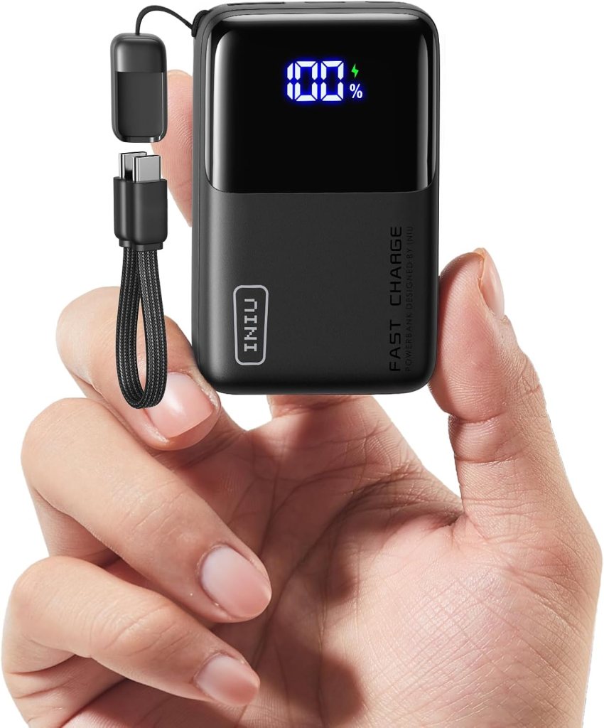 A person holding a compact INIU portable charger with a digital display showing the battery percentage.