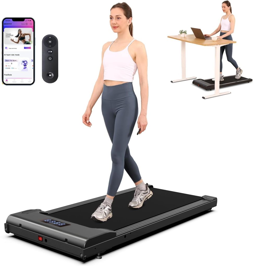 A woman walking on a portable under desk treadmill while holding a remote control, with a smartphone displaying workout settings nearby.