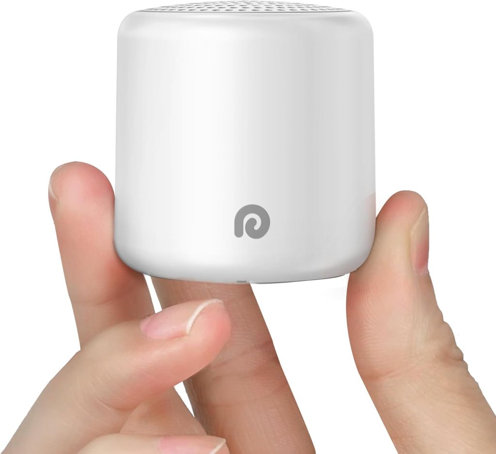 A person holding a small, white portable white noise machine in their hand.