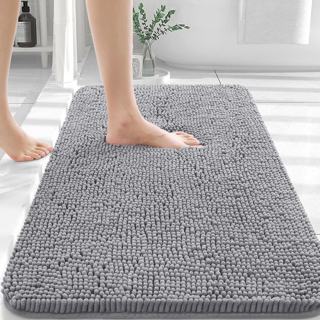A person stepping onto a soft grey bathroom rug with a textured surface in a bright bathroom setting.